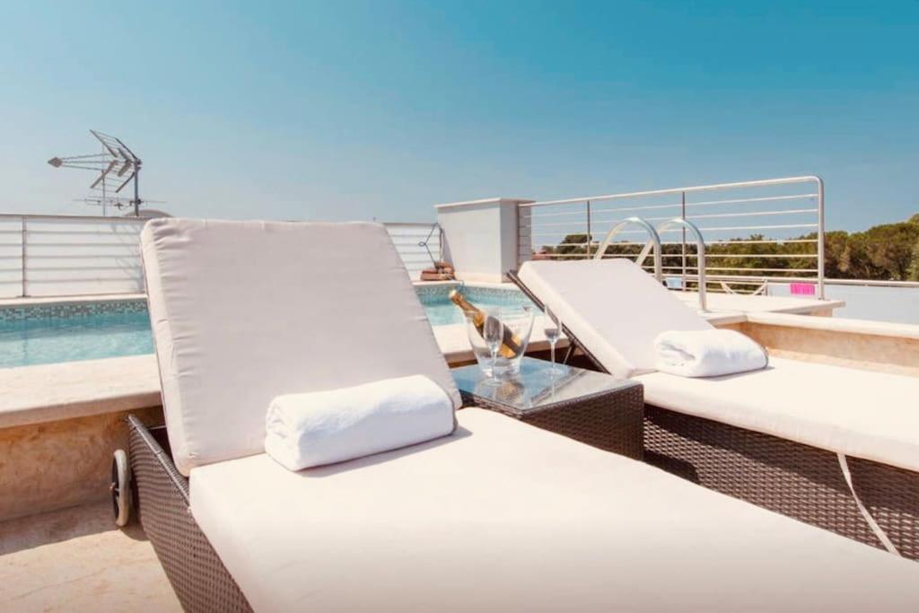 2 witte ligstoelen op een balkon met een zwembad bij Luxury Penthouse Aranova in Aranova