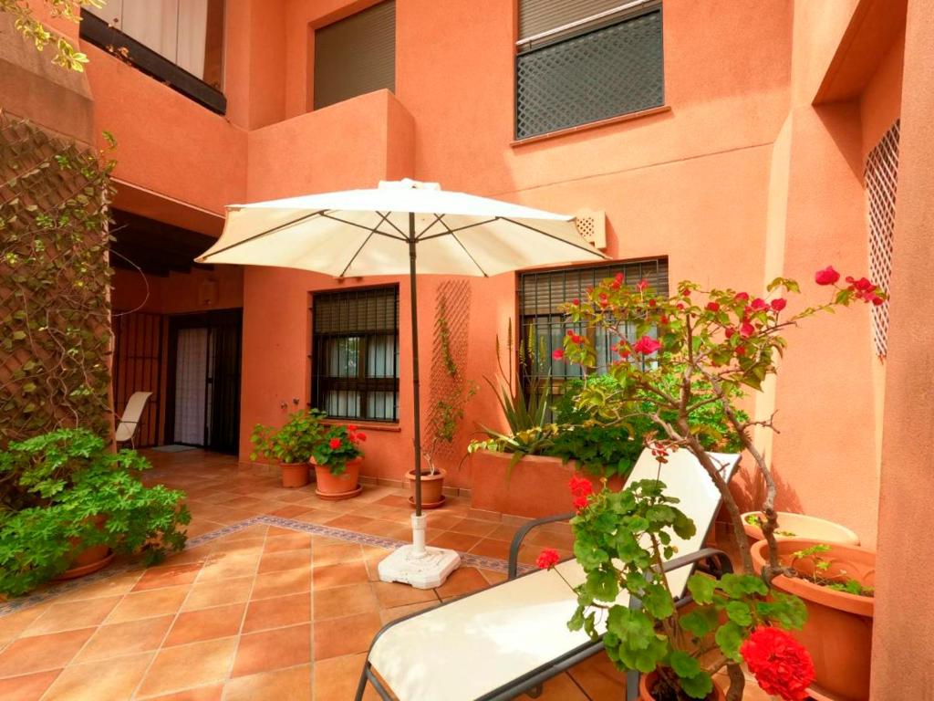 une terrasse avec un parasol et des plantes en pot dans l'établissement Apartamento Los Moriscos Golf Playa Granada, à Motril