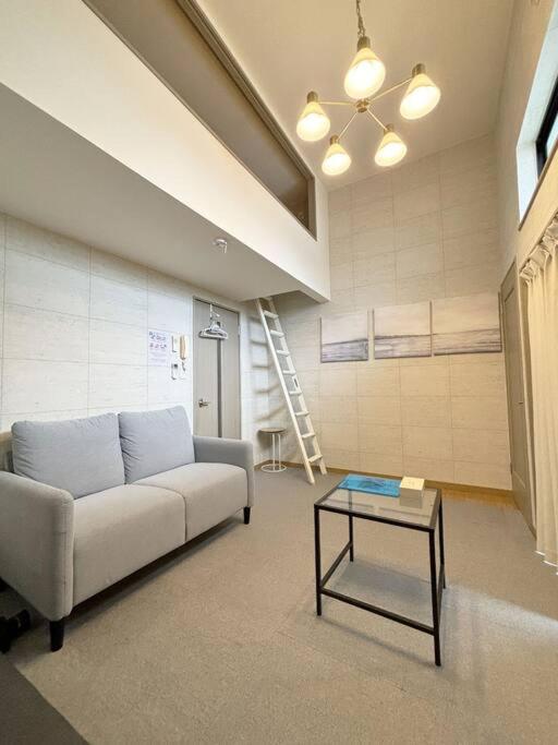 a living room with a couch and a table at エスポアール新町Ⅵ(101) in Hanabatachō