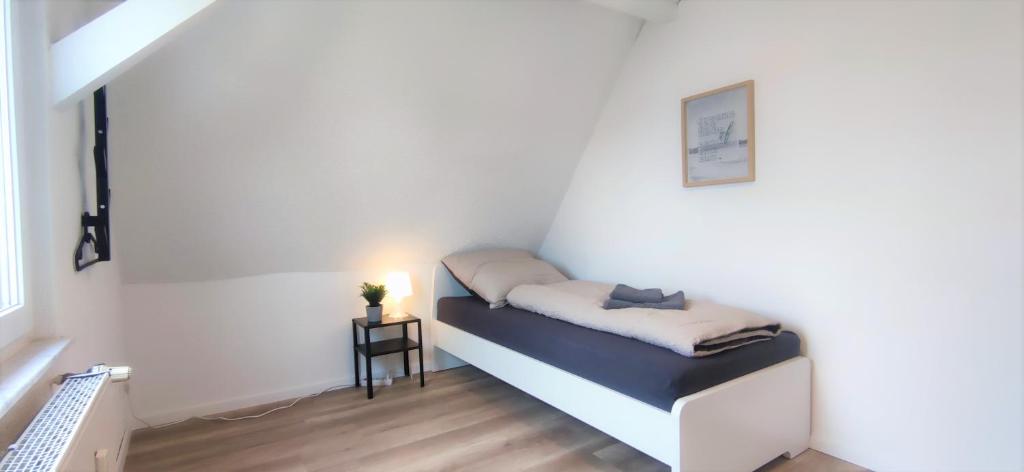 a small bed in a white room with a side table at Monteurwohnung in Trossingen bei Villingen-Schwenningen in Trossingen