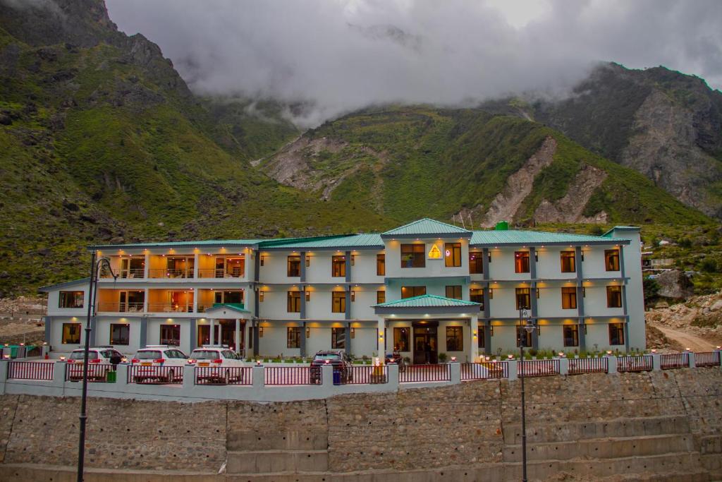 a hotel with cars parked in front of a mountain at Amritara The Avadh in Badrīnāth