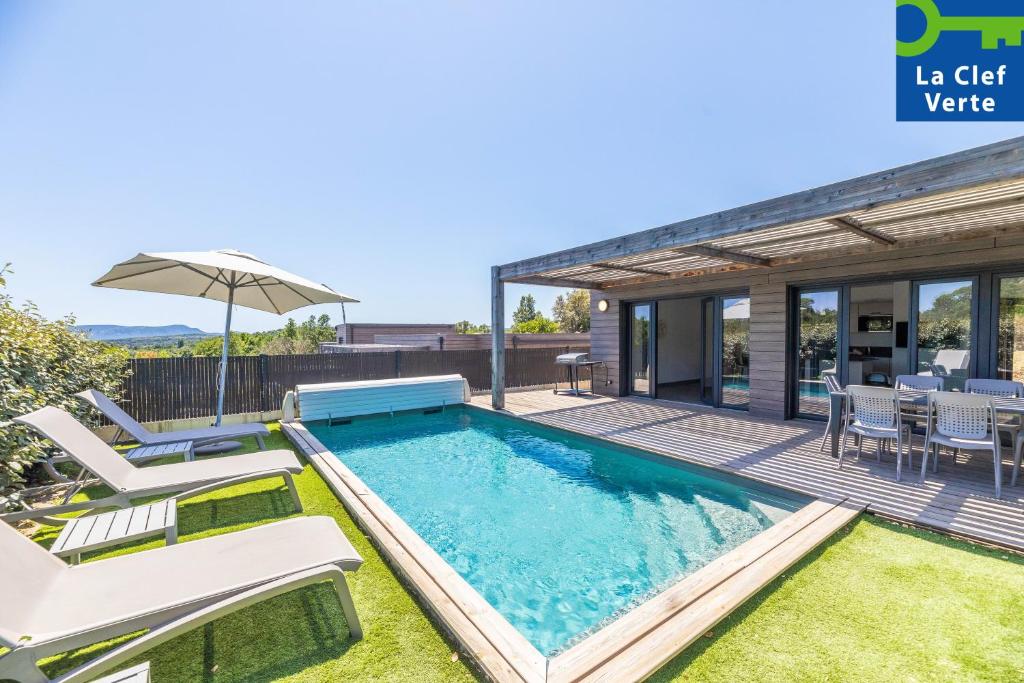 a swimming pool with chairs and an umbrella on a house at Résidence Pierre & Vacances Premium Les Terrasses d'Arsella in Porto-Vecchio