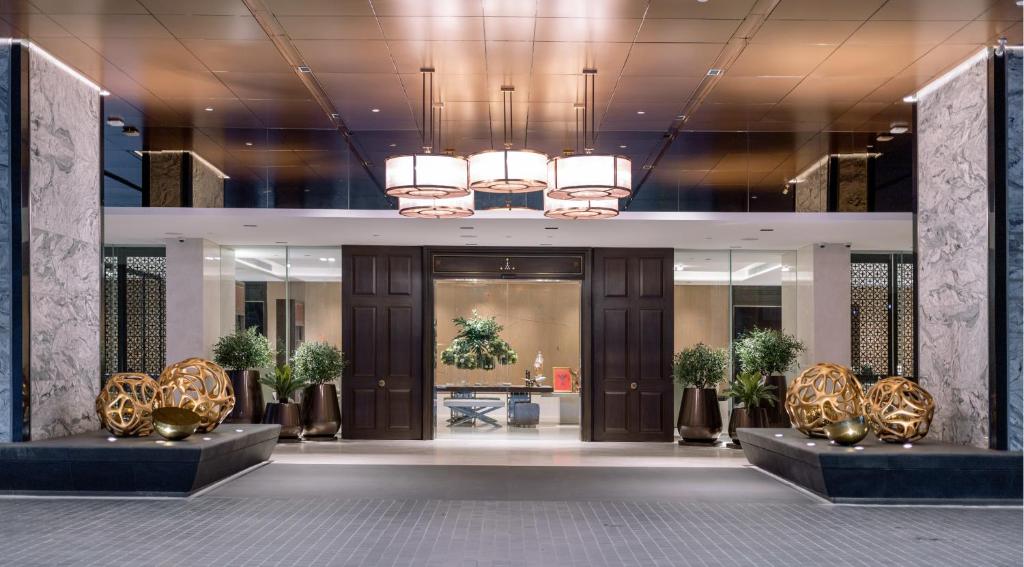 A formal hotel entrance lobby is framed by marble columns, pendant lights, and symmetrical decor.