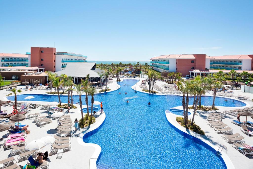 Un resort con dos piscinas, sillas y palmeras. en Hotel Best Costa Ballena, en Costa Ballena