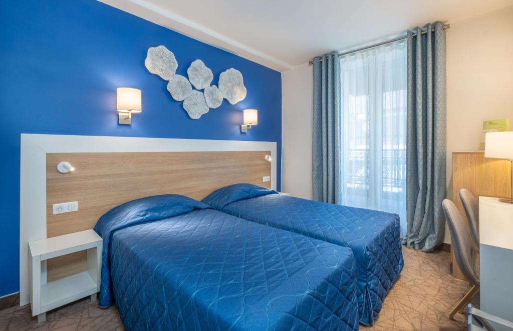 Dormitorio azul con cama y ventana en Hotel Terminus Montparnasse en París