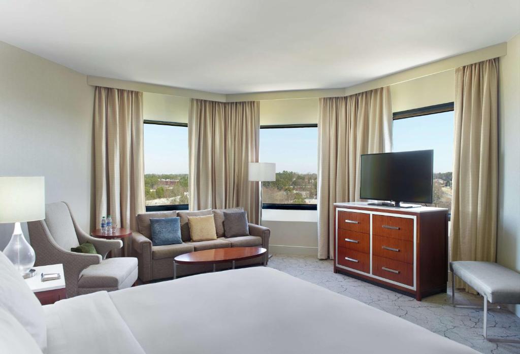 a hotel room with a bed and a television at Hilton Atlanta Northeast in Norcross