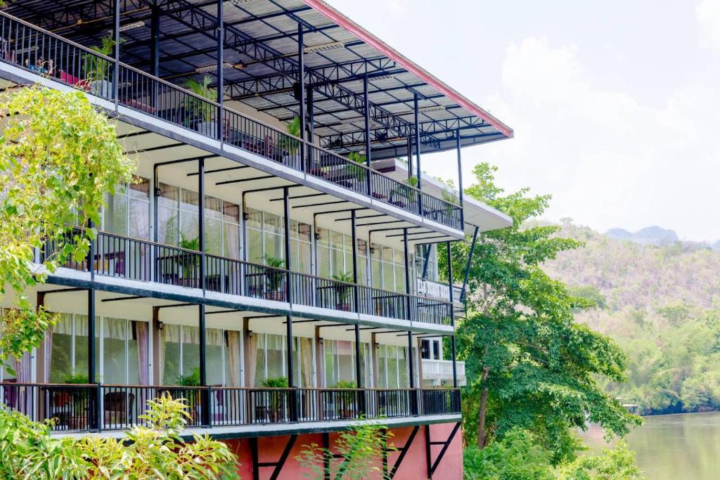 un edificio con balcones a orillas de un río en เพชรมณีกาญจน์ บีช รีสอร์ท, en Ban Plai Huai Kaeng Riang