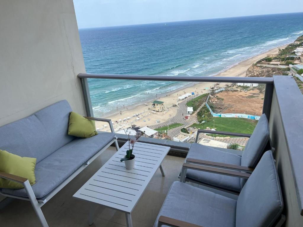 a balcony with a couch and a table and the beach at Luxury Sea View Apartment in Herzelia 