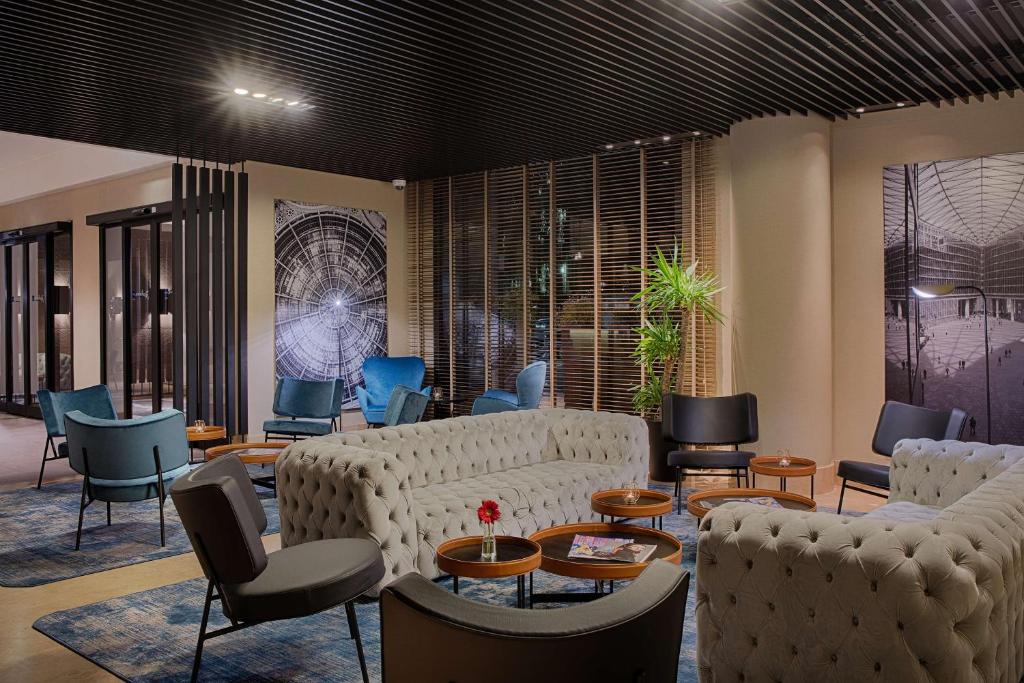 a living room with couches and tables and chairs at Radisson Blu Hotel Milan in Milan