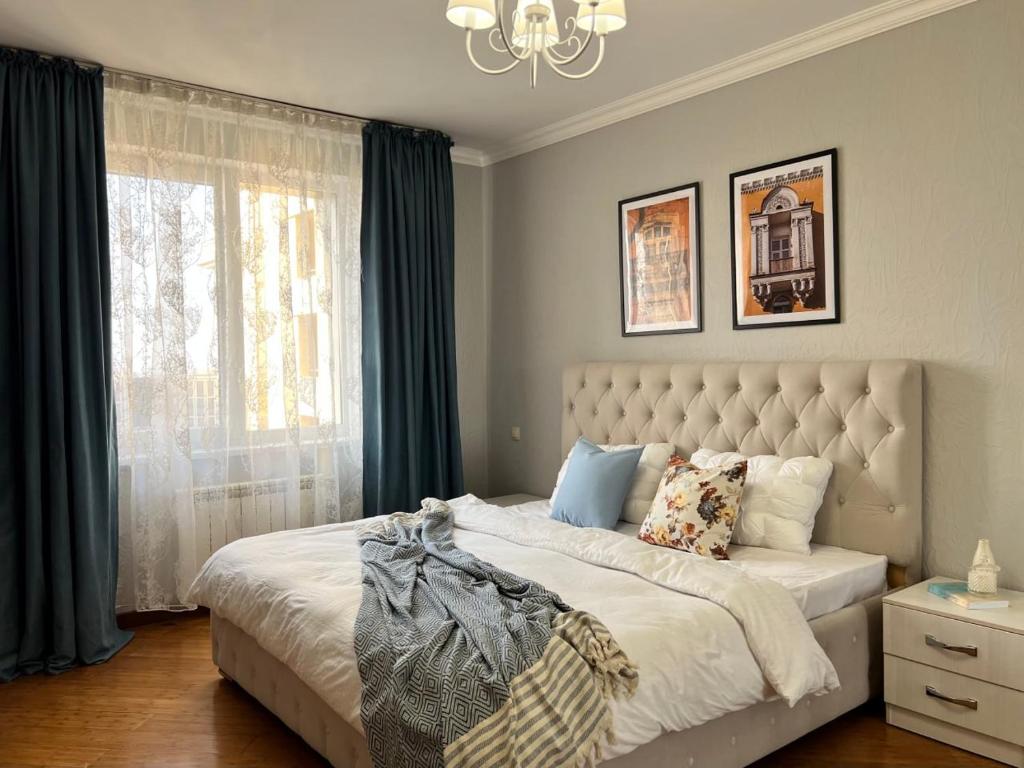 阿拉木圖的住宿－Уютная квартира в центре Алматы с потрясающими видами，一间卧室设有一张大床和一个窗户。