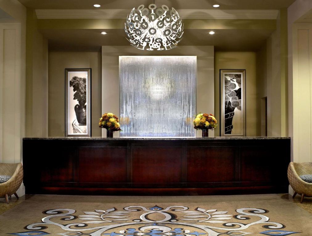 a lobby with a reception desk and a chandelier at The Alexis Royal Sonesta Hotel Seattle in Seattle