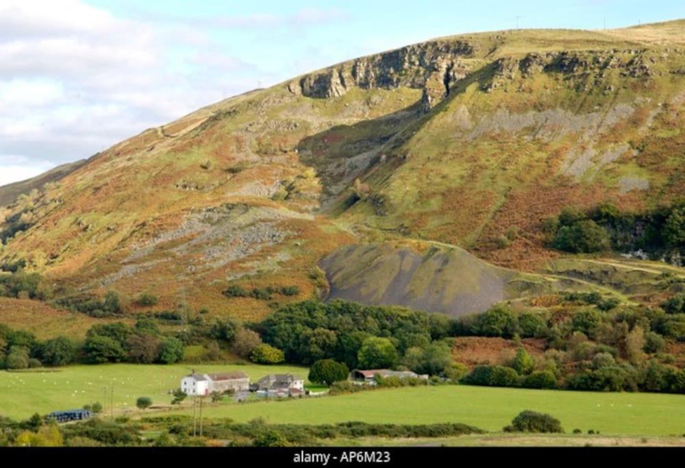 a large hill with a house and a green field at Mountain View Cottage sleep 6 sofabed quaint and quirky cottage in Ystalyfera