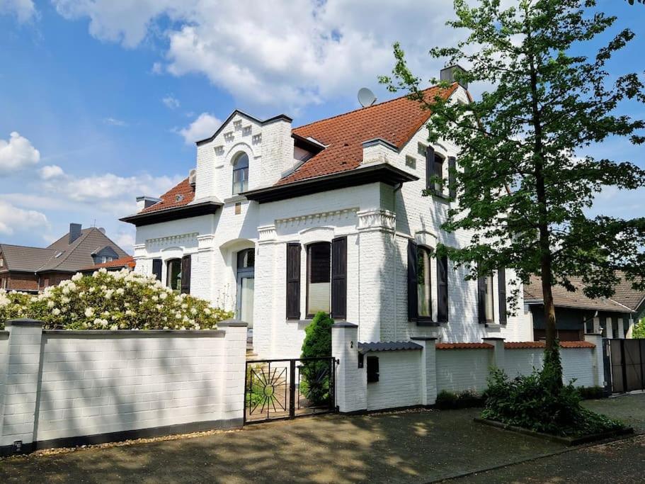 una casa blanca con una valla delante en Historische Villa mit Garten, Luxus, en Meerbusch