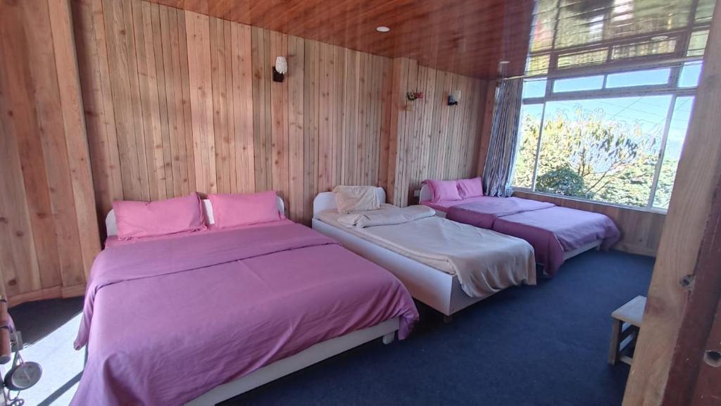Duas camas num quarto com paredes de madeira em Taiga Homestay, Lepchajagat, Darjeeling em Darjeeling
