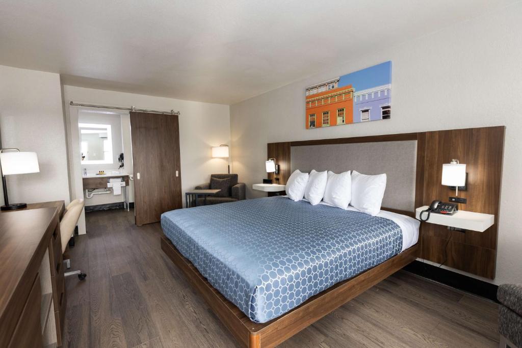 a hotel room with a bed with a blue bedspread at Bhagat Hotels Stone Mountain Atlanta BW Signature Collection in Tucker