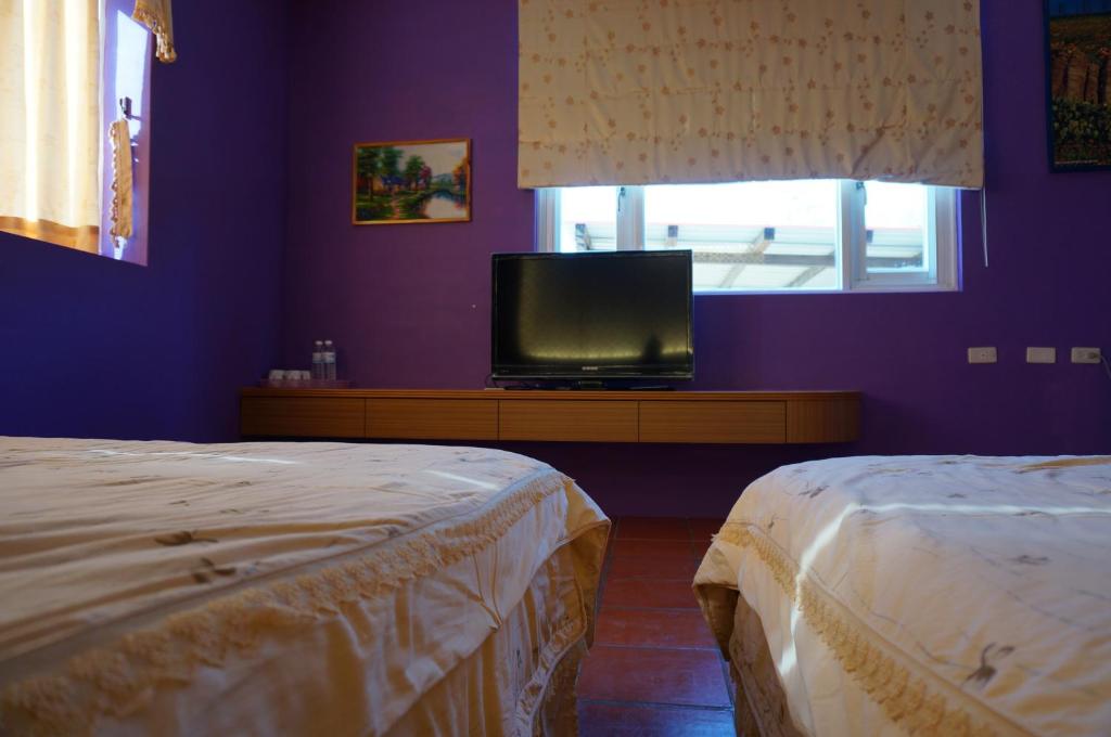 two beds in a room with a tv and a window at See Starsea Guest House in Magong