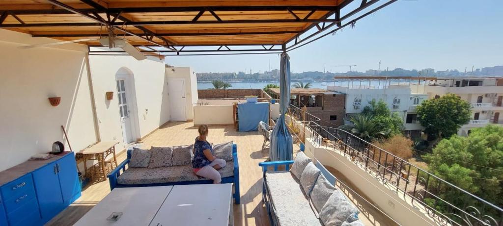 a woman sitting on a couch on a balcony at House of Dreams apartments Luxor in Luxor