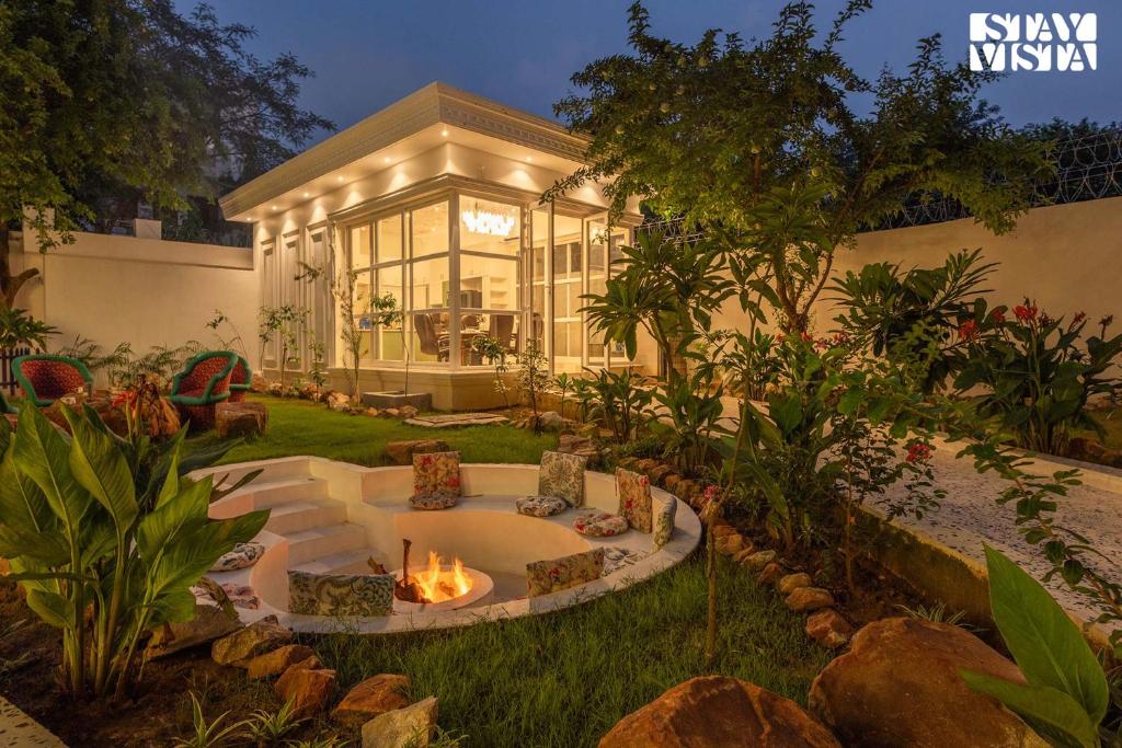 um quintal com uma fogueira no quintal em StayVista's Indraj Manor - Roman-Inspired Villa with Posh Interiors, Mesmerizing Garden & Outdoor Fireplace em Nova Deli