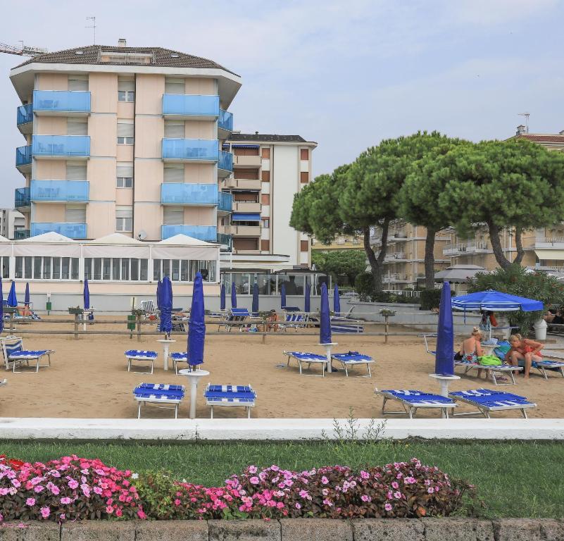 plaża z niebieskimi leżakami i parasolami przed budynkiem w obiekcie Hotel La Bussola w mieście Lido di Jesolo