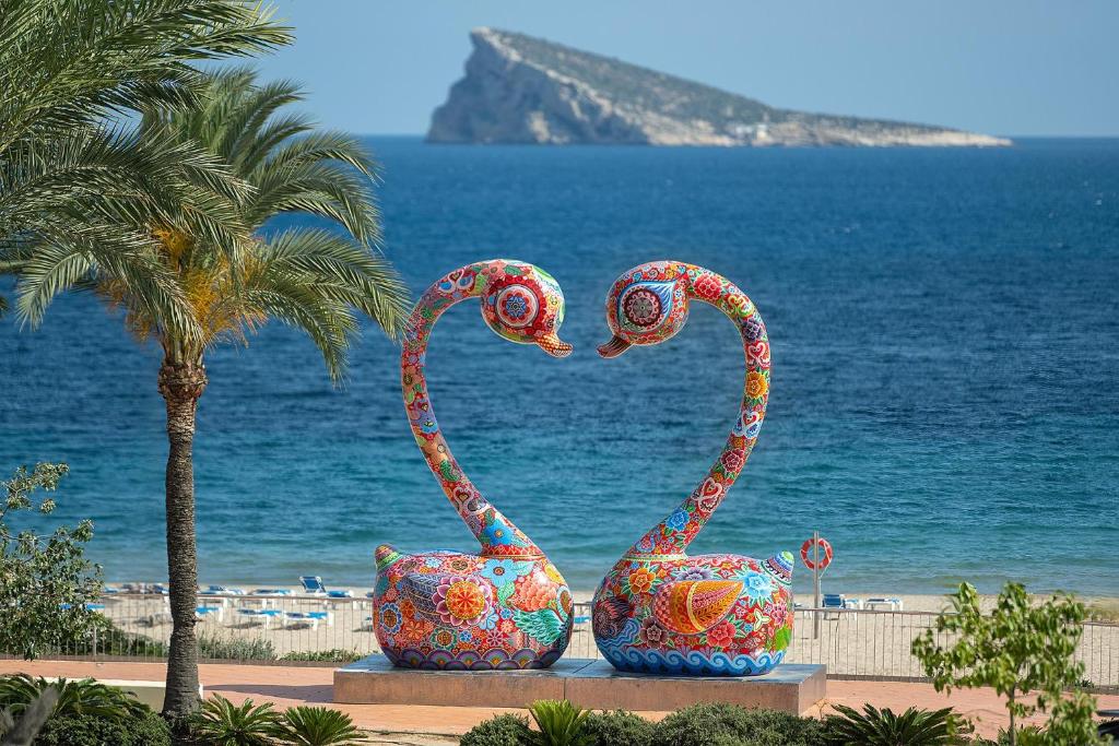 two sculptures of swans sitting next to the ocean at Hotel Poseidon Playa in Benidorm