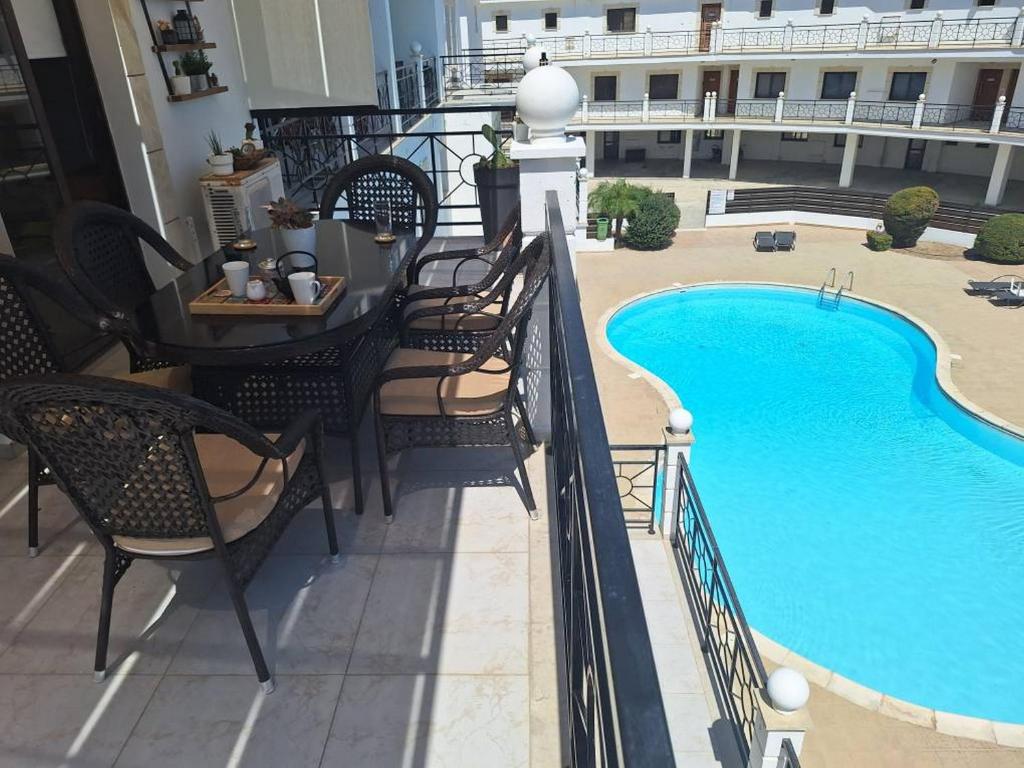 balcón con mesa y sillas y piscina en Paramount Gardens Resorts D204, en Tersephanou
