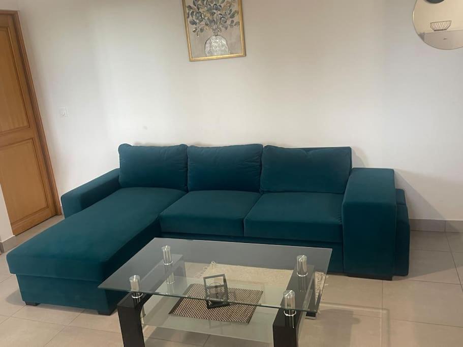 ein blaues Sofa im Wohnzimmer mit einem Glastisch in der Unterkunft L5/villiers-le-bel proche Roissy in Villiers-le-Bel