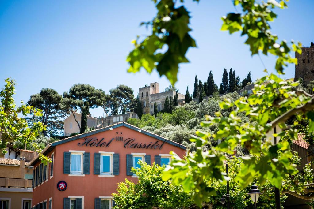 ein Gebäude auf einem Hügel mit einem Schloss im Hintergrund in der Unterkunft The Originals Boutique, Hôtel Cassitel, Cassis in Cassis