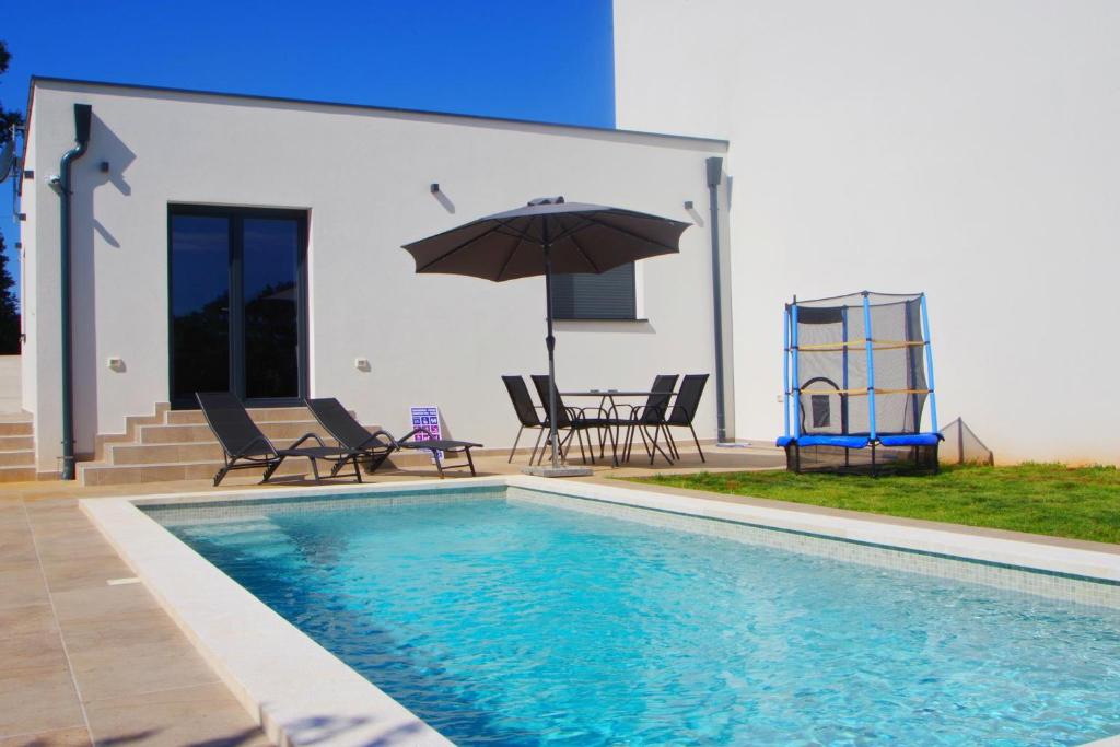 a pool with chairs and an umbrella next to a house at Holiday house with private pool in village Šišan in Šišan