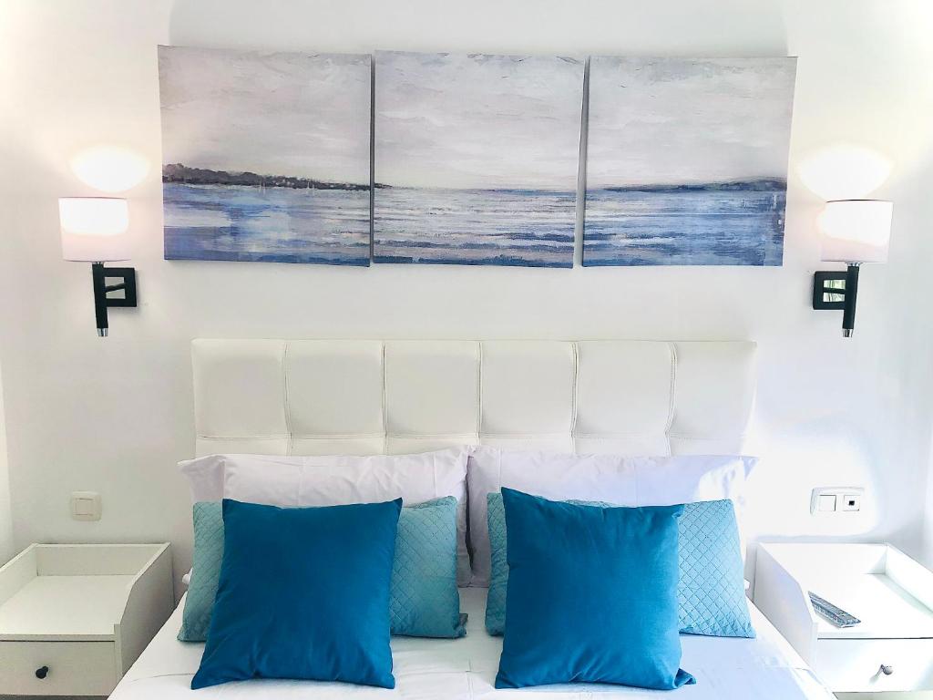 1 dormitorio con almohadas azules y pinturas encima de una cama en La Terraza del Campo de golf Playa Piscina y parking gratuito en Torre de Benagalbón