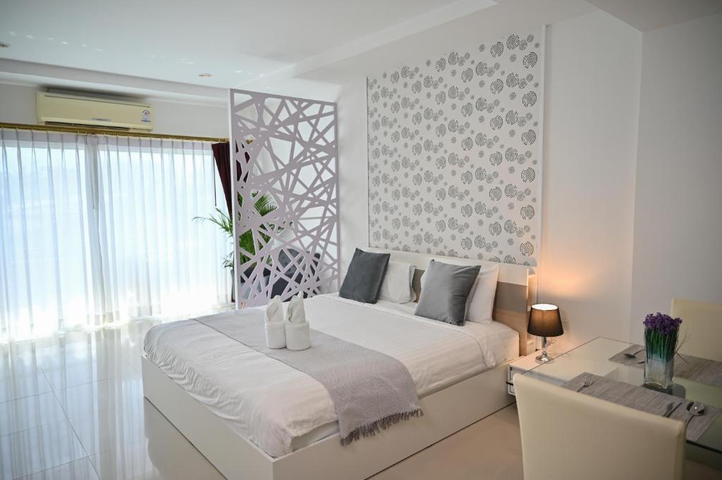 een witte slaapkamer met een groot bed en een bureau bij Sivana Place Phuket in Bang Tao Beach