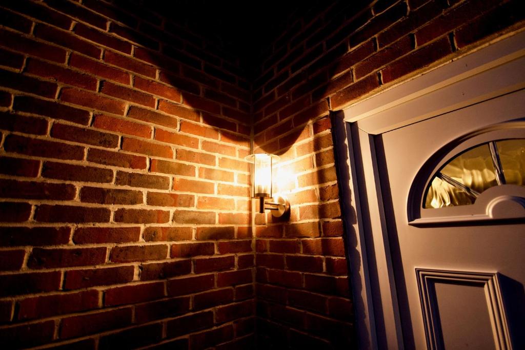a light next to a brick wall with a door at Mill Lane Refurbished 2 Bedroom Apartment in Newbury