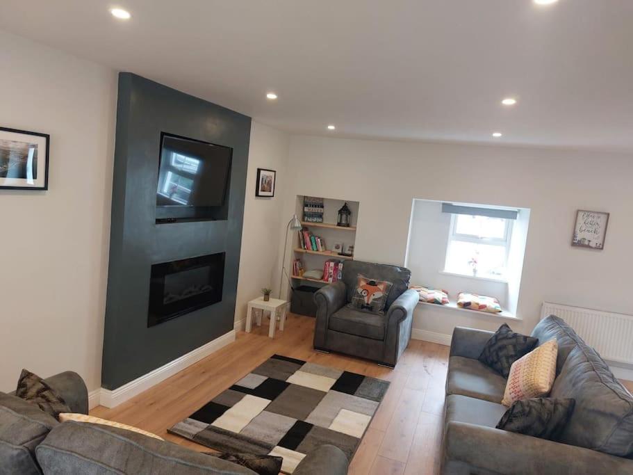 uma sala de estar com dois sofás e uma televisão em Stunning New 3 Bed Townhouse em Belmullet