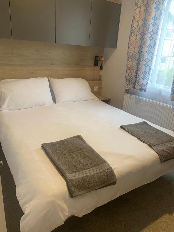 1 dormitorio con 1 cama grande y 2 toallas. en Hafan Y Môr Caravan - Pwllheli en Chwilog
