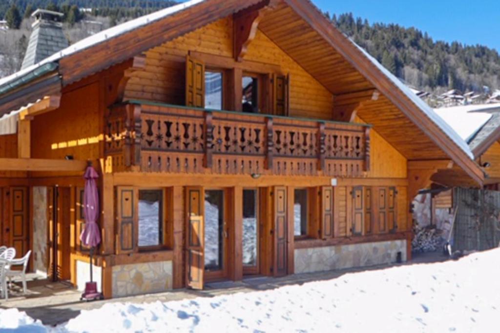 une cabane en rondins avec une grande terrasse dans la neige dans l'établissement Chalet R'Mize, aux Gets