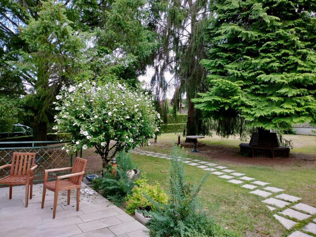 a park with two benches and trees and flowers at Les Beaux Sapins 2 in Rochechouart