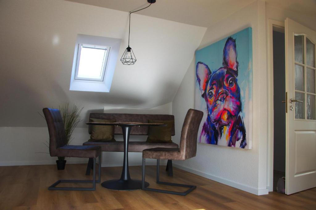 ein Esszimmer mit einem Tisch und einem Gemälde eines Hundes in der Unterkunft Roof Lounge in Südbrookmerland