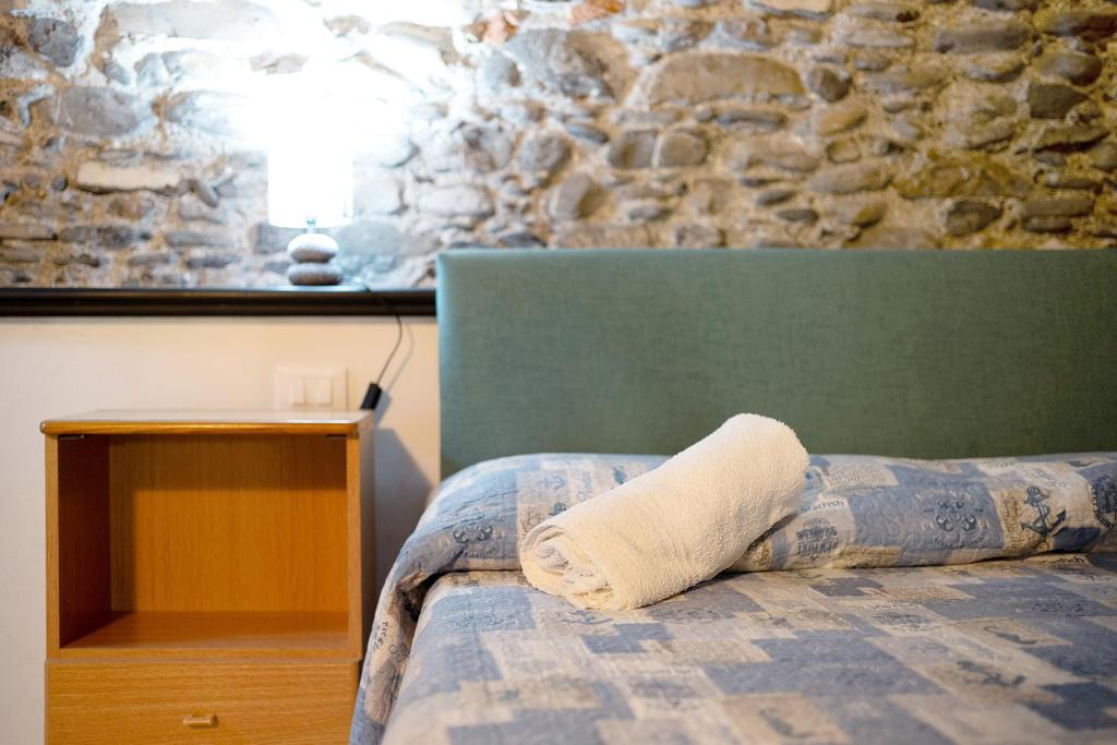 uma cama com uma almofada com uma parede de pedra em Dipinti, borgo dei pescatori em Cervo