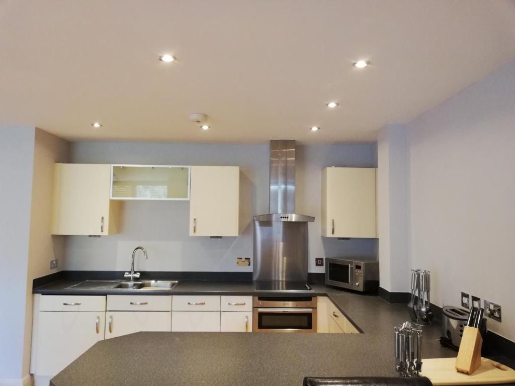 uma cozinha com armários brancos e um lavatório em Pelican House is an exclusive contemporary development em Newbury