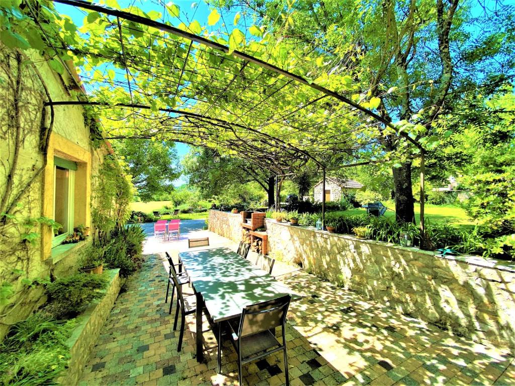 a patio with a table and chairs and a stone wall at CHAMBRES D'HOTES 2 à 4p ou GITE DE GROUPE 15p, 7 ch, 6 sdb, parc et salle de réception in Villeneuve-de-Berg