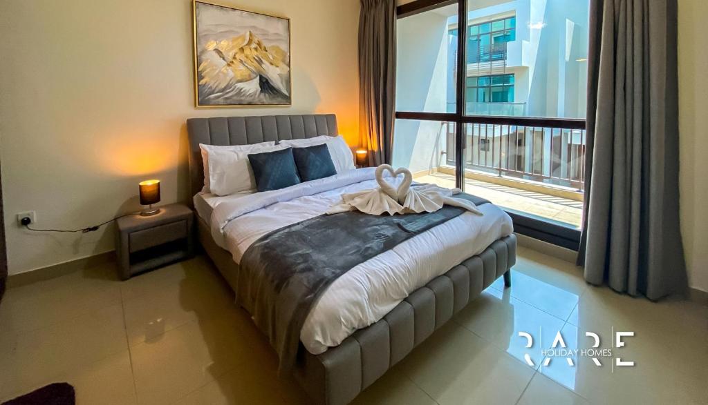 a bedroom with a bed and a large window at Rare Holiday Homes presents Large 1 Bed in a peaceful community of JVC -La Riviera Estate B R106 in Dubai