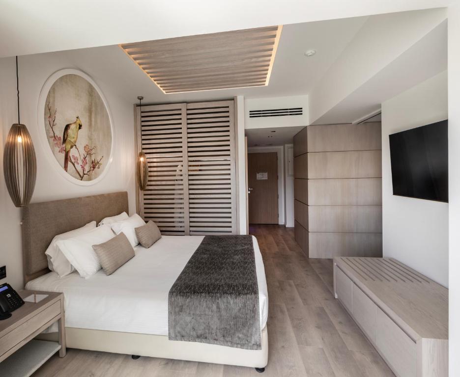 a bedroom with a white bed and a television at NissiBlu Beach Resort in Ayia Napa
