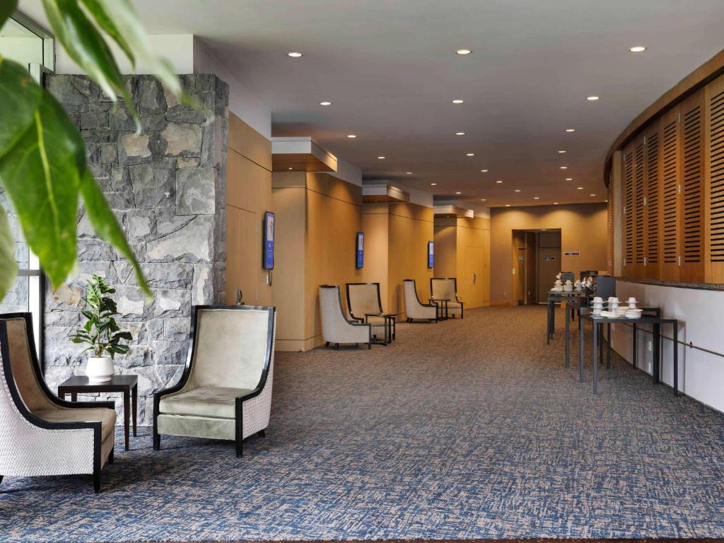 a waiting room with chairs and a stone wall at Novotel Auckland Ellerslie in Auckland
