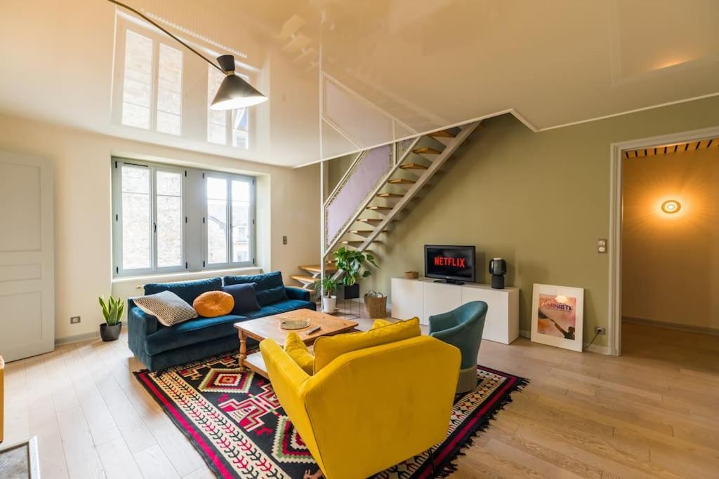 ein Wohnzimmer mit einem blauen Sofa und gelben Stühlen in der Unterkunft Appartement d'exception - proche de la mer in Saint-Brieuc