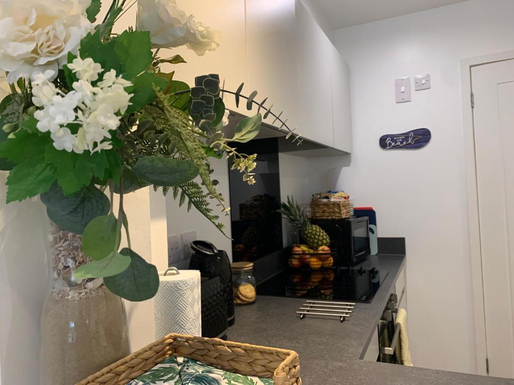a kitchen with a vase of flowers on a counter at BOURNEMOUTH Nr TOWN BEACH TRAIN COACH SHOPS Lovely ENTIRE APARTMENT ALLOWS QUIET GOOD DOGS in Bournemouth
