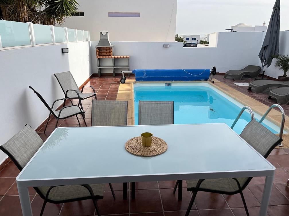 een tafel en stoelen voor het zwembad bij HOUSE WHITE BEACH in Playa Blanca