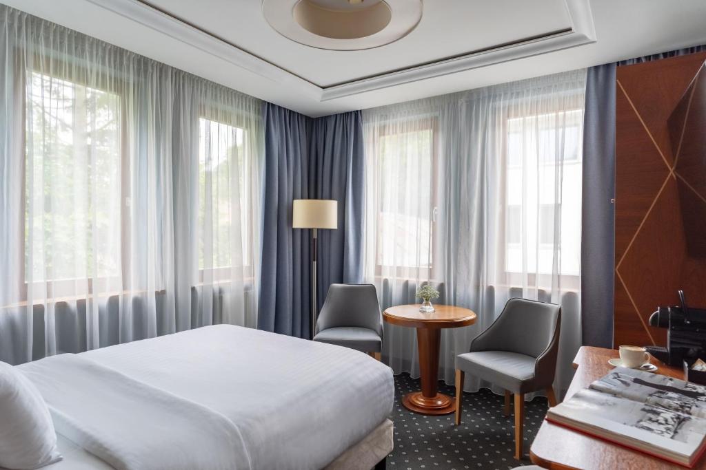 a hotel room with a bed and a table and chairs at Haffner Hotel & SPA Sopot - Destigo Hotels in Sopot