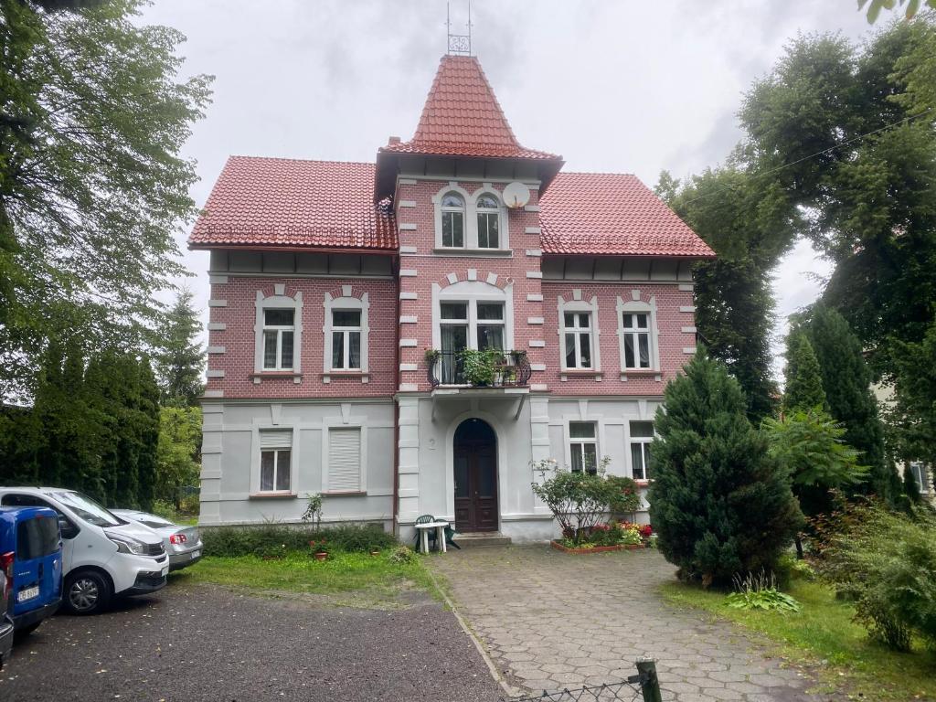 Una gran casa roja y blanca con una torre en Apartamenty przy Parku Szwedzkim, en Szczawno-Zdrój