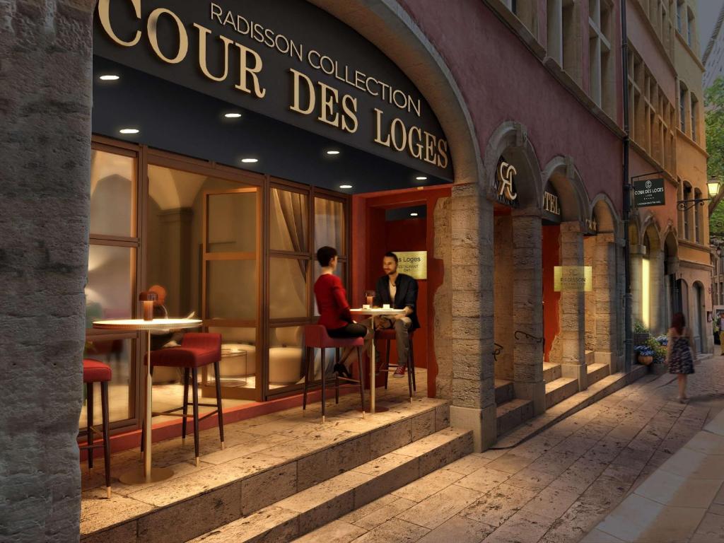 a couple sitting at tables outside of a store at Cour des Loges Lyon, A Radisson Collection Hotel in Lyon