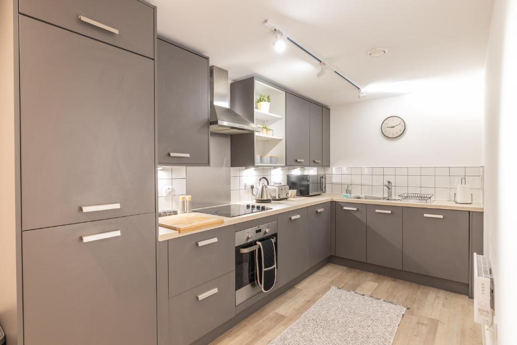 a kitchen with gray cabinets and stainless steel appliances at New 1 Bed 1 Bath Apartment in Cool Digbeth in Birmingham