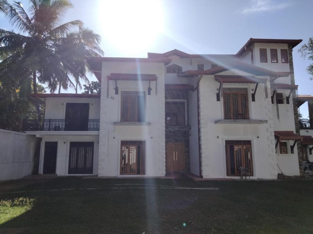 a white house with a palm tree in front of it at Rose Cottage in Digana